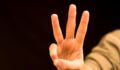 Photo of a hand holding up three fingers.